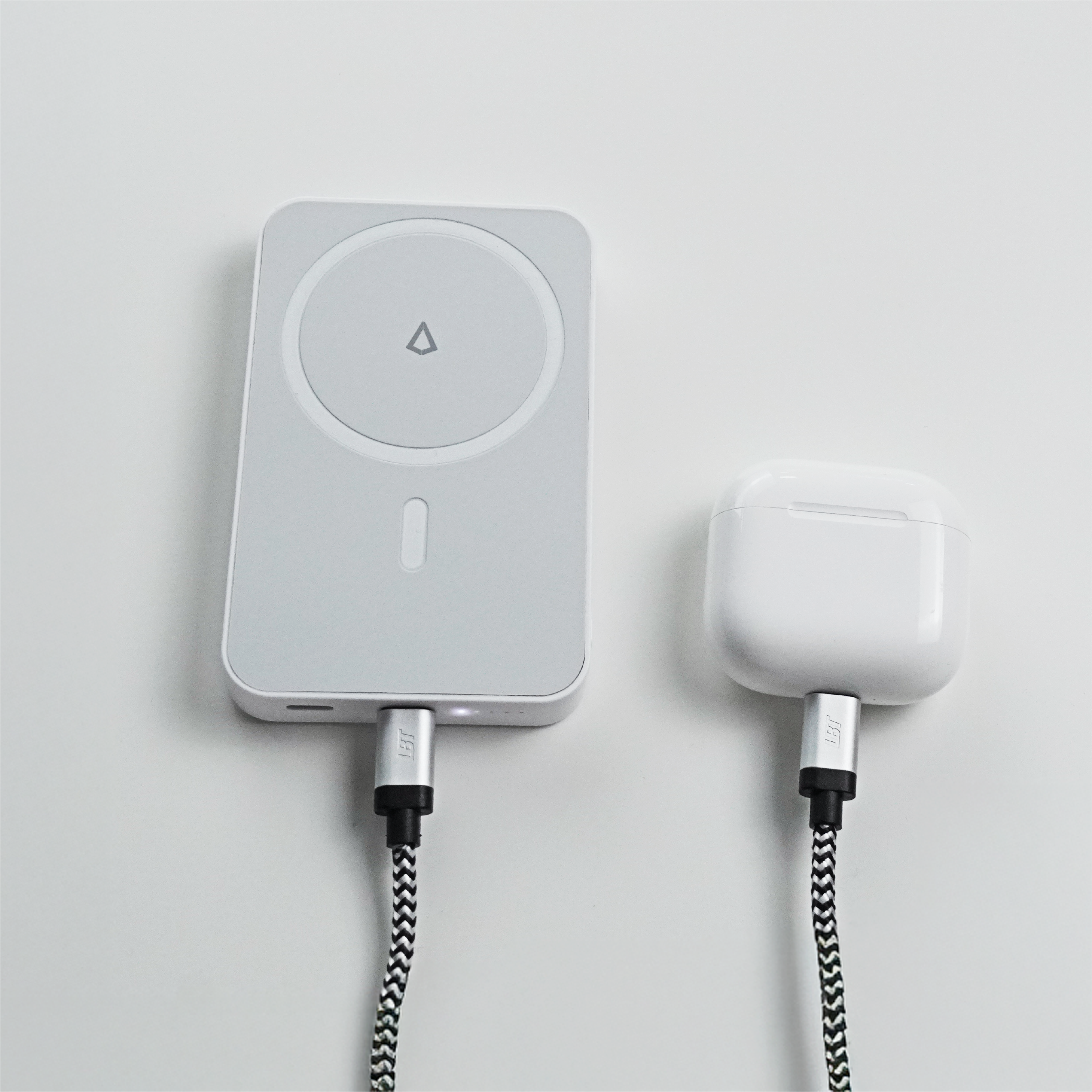 White wireless charger with cable charging an airpods on a light gray background