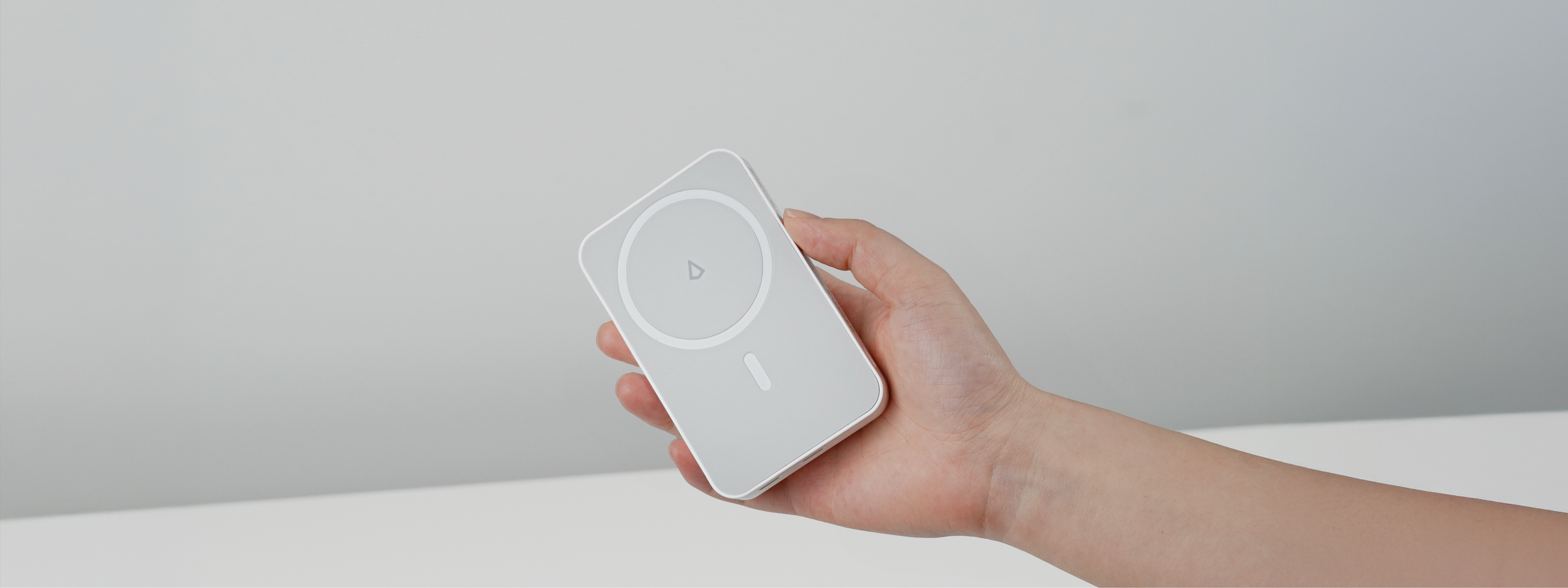 Hand holding a white Power bank against a plain background